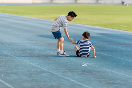 Young Asian boy running on blue track in the stadium during day time to practice himself.の写真素材