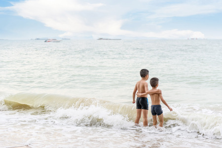 Young Asian Thai boy playing in a sea water together with his brotherの写真素材