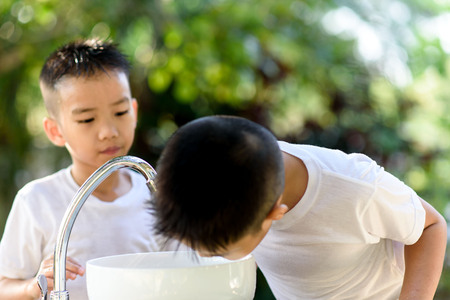 Selective focus and brand new faucet and kid hand taking water.