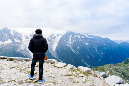 Selective focus at Young Asian tourist looking to beautiful View of Mont Blanc Massif with the grass...