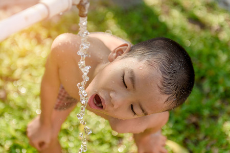 Close up young asian boy taking water from old faucet in the garden. Water shortage and drought conceptの写真素材