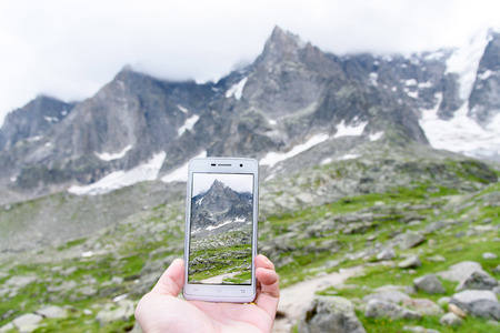 Hand holding smartphone taking photo of Aiguile du Chardonnet a beautiful view of Mont Blanc Massif...