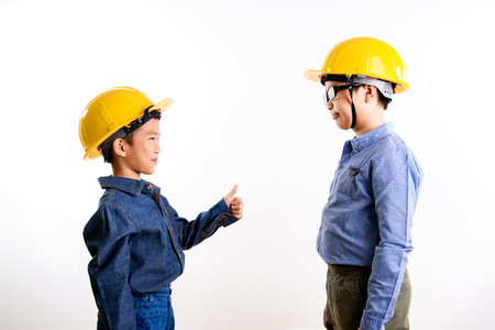 Young asian Thai boy in yellow safety helmet pretend to be engineering during construction area.の写真素材
