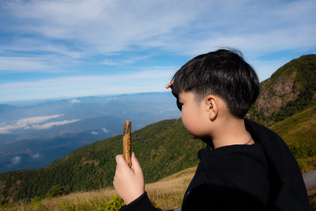 Preteen Asian Thai boy travel on a top of Mountain in Thailand and with above of cloud and fog...