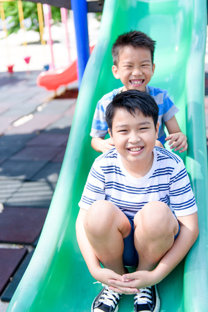 Young asian Thai boy climb to slide on the color full slider playground during summerの写真素材