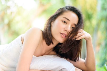 Selective focus at Young Asian woman face feel relax after oil massage at garden in spa resort.の写真素材