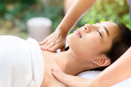 Selective focus at Young Asian woman face feel relax during body and sholder massage at garden in spa resort.の写真素材