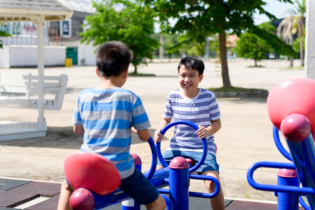 Happy Two young asian boy play on the balance bar at outdoor playground under the strong sunlight in summer time.の写真素材