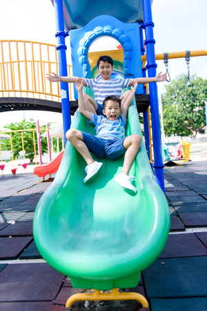 Young asian Thai boy climb to slide on the color full slider playground during summerの写真素材
