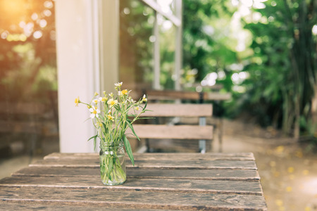 Selective focus at flowers in a transparent vase on wooden table feel lonely concept at the resturant.の写真素材
