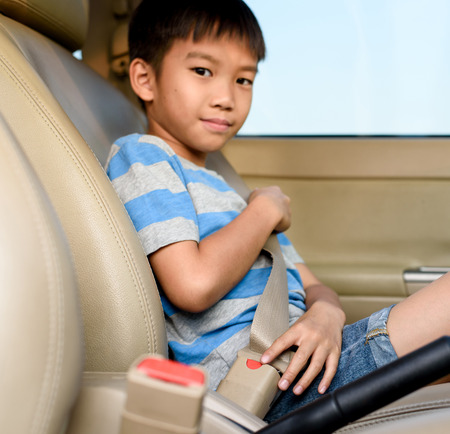 Young asian boy using safety belt in a car during travel.の写真素材