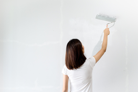 Young Asian woman renovate and paint color on a old white wall in a bed room.の写真素材
