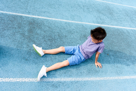Young Asian Than boy resting after running on the blue track.の写真素材