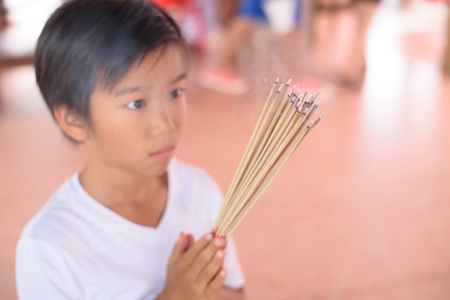Young boy pray with incense stick at templeの写真素材
