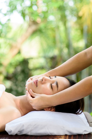 Selective focus at Young Asian woman face feel relax during face massage at garden in spa resort.の写真素材