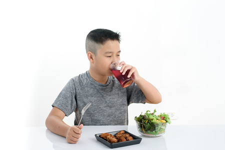Young Asuab Thai boy drink red soda water during eat deep fry chicken and mix vegetable saladの写真素材