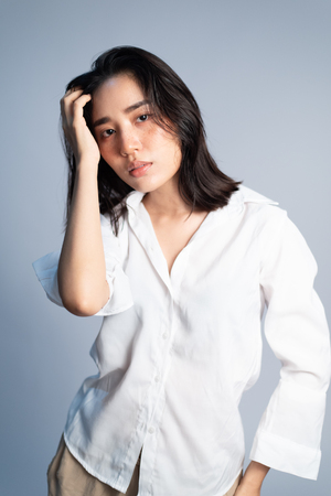 Shooting studio portrait of young Asian Thai woman with white shirt on white background. Relax and mordern concept.の写真素材