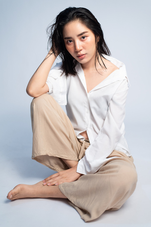 Shooting studio portrait of young Asian Thai woman with white shirt on white background. Relax and mordern concept.の写真素材