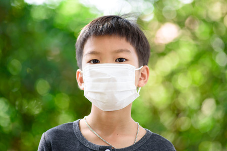 Young Thai boy put a mask on his face to protect a dust in a pollution air.の写真素材