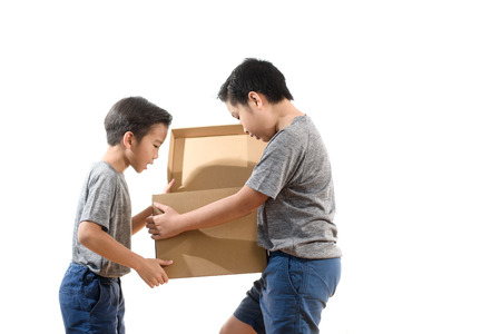 Two young Asian boy open a brown carton box and surprise an inside on white background.