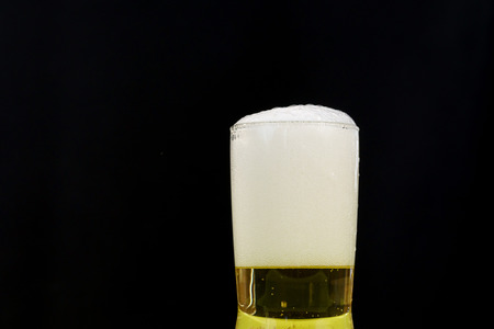 Selective focus at beer in small glass on black background.