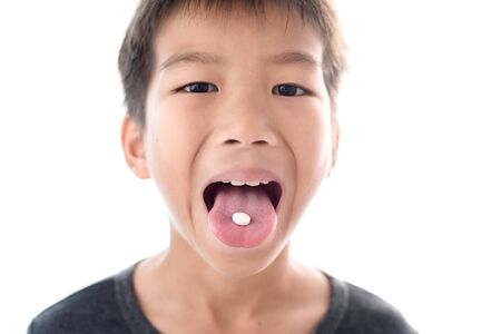 Selective focus at a white pill on a tongue of young boy.の写真素材