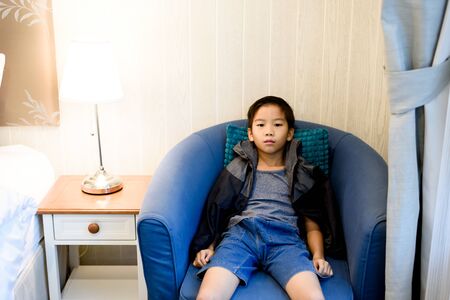 Young Asian boy sit alone in a bedroom.の写真素材