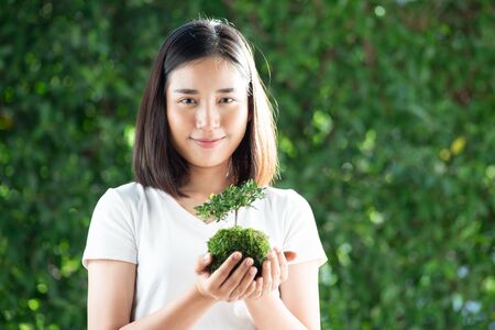 Selective focus at young Asian Thai woman carry little seeling plant. Earth day concept.の写真素材