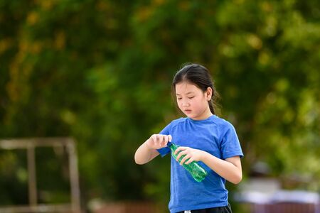 Young Asian girl open a cap from a plastic bottle to drink.