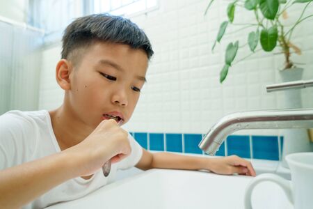 Young Asian boy brush his teeth in a bathroomの写真素材