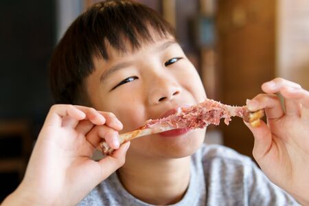 Young Asian boy eat fried port and salad in a resturant.の写真素材
