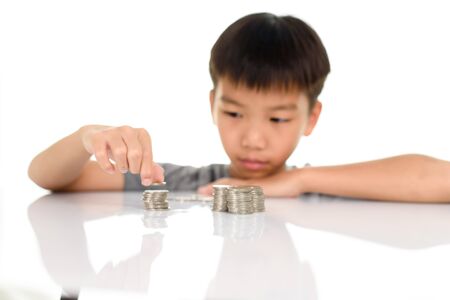 Selective focus of young Asian boy stack a coin tower
