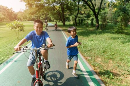 Young Asian boy ride a bicycle in a park during summer day.の写真素材