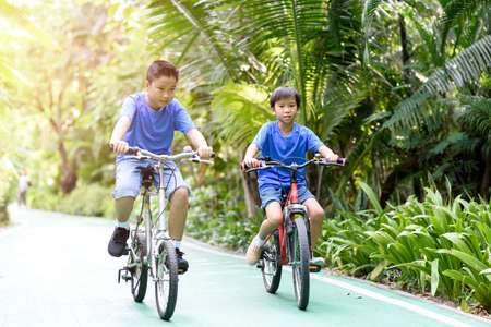 Young Asian boy ride a bicycle in a park during summer day.のeditorial素材