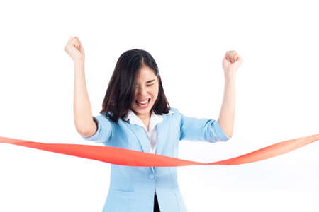 Young Asian Thai woman happy when reach a finish red ribbon line. Competition and success concept.の写真素材