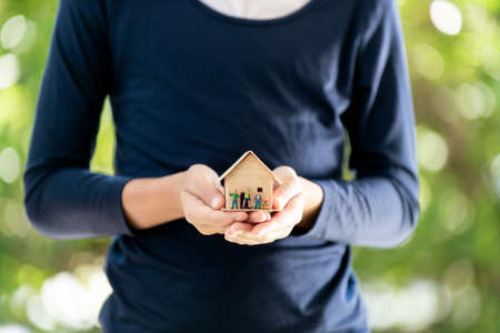 Selective focus at small wooden house in young boy hands in front of green background from tree in a garden.の写真素材