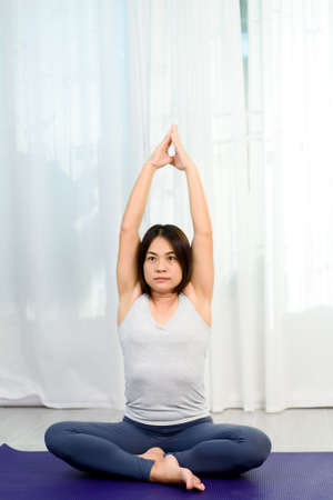 Young Asian woman do yoga in a bedroom during morning.
