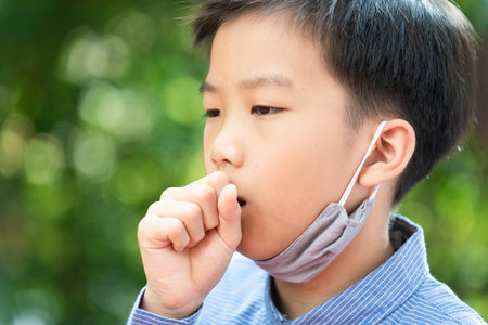 Selective focus young Asian boy with face mask to protect visus, on grean backgroundの写真素材
