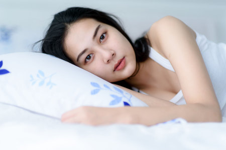 Selective focus at young Asian woman lay on a bed after waking up in the morning.の写真素材