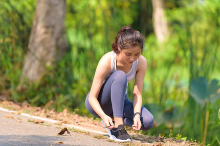 Young Asian boy and girl take care their shoe lace before running in a park.の写真素材