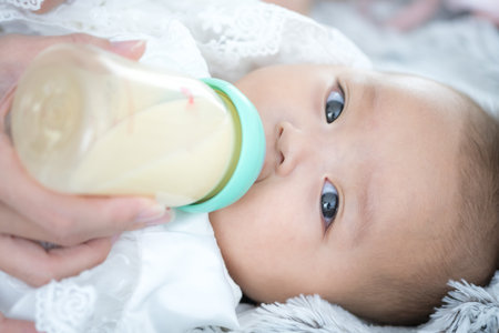 Close up baby sucking milk from bottleの写真素材