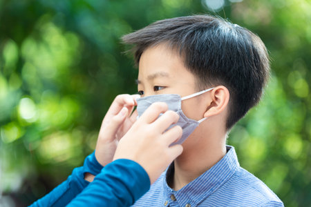 Selective focus young Asian boy with face mask to protect visus, on grean backgroundの写真素材