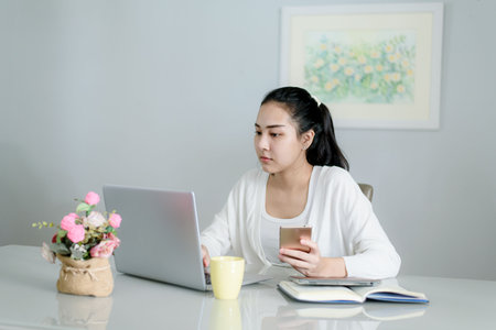 Young Asian woman working at home during covid-19 pademic, to keep social distancing.の写真素材