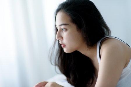 Selective focus at young Asian woman lay on a bed after waking up in the morning.の写真素材