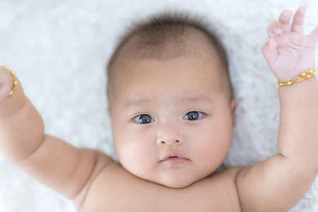Portrait Happy Asian female baby on white bedの写真素材