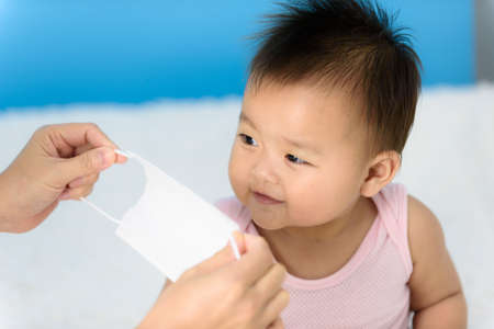 Close up mom wearing surgical mask to Asian baby