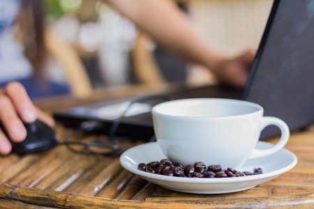 woman working on laptop in a coffee shop on wooden tableの写真素材