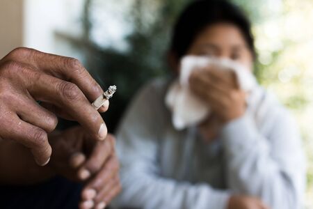 Man is smoking cigarette and woman is covering her face. A lot of smoke around..Stop Smoking Concept.の写真素材