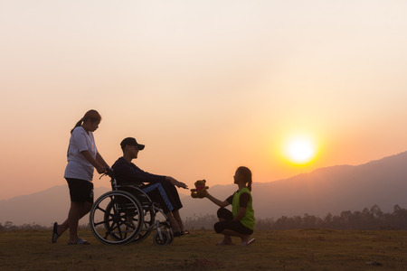 Happy boy in wheelchair with friends Evening sunset.Concept happy child disabledの写真素材