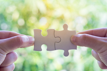 Closeup hand of man connecting jigsaw puzzle with sunlight effect, Business solutions, success and strategy conceptの写真素材